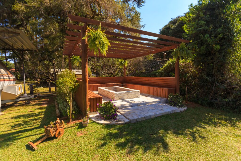 pexels-photo-13871294-13871294 Spacious wooden gazebo in a lush garden setting with green foliage and stone flooring.