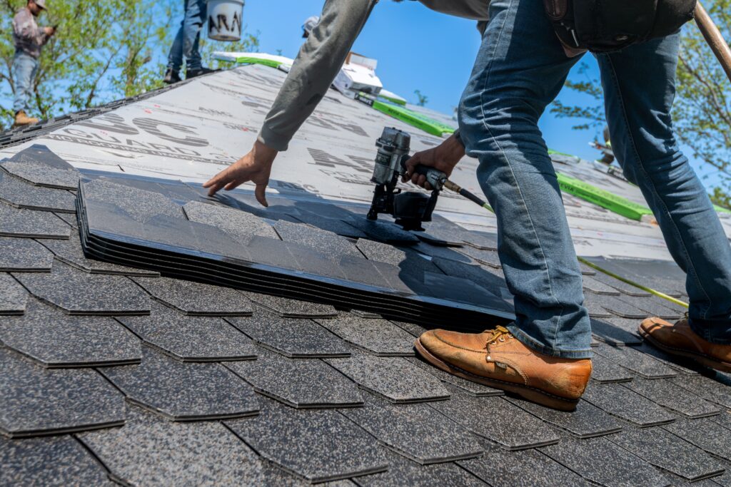 pexels-photo-33404248-33404248 Roofer using nail gun for shingle installation on residential roof.